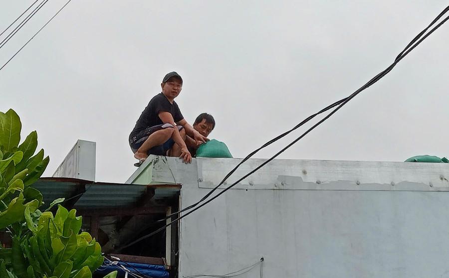 Sáng 6-11, anh Huỳnh Thanh Thất, ở khu phố Hải Bắc tranh thủ chằng chống lại mái nhà, rồi di chuyển đến nhà người thân để trú tránh bão. Ảnh: Ngọc Nhuận anh-huynh-thanh-that-tranh-thu-chang-chong-them-mai-nha-roi-so-tan-den-noi-an-toanjpg.jpg