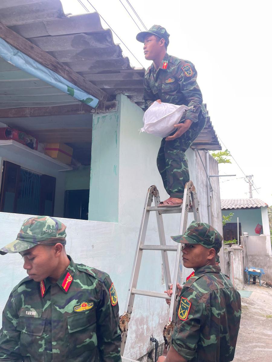 Lực lượng vũ trang hỗ trợ người dân xã đảo chằng chống nhà cửa. Ảnh: Thành Long giang-chong-bao.jpg