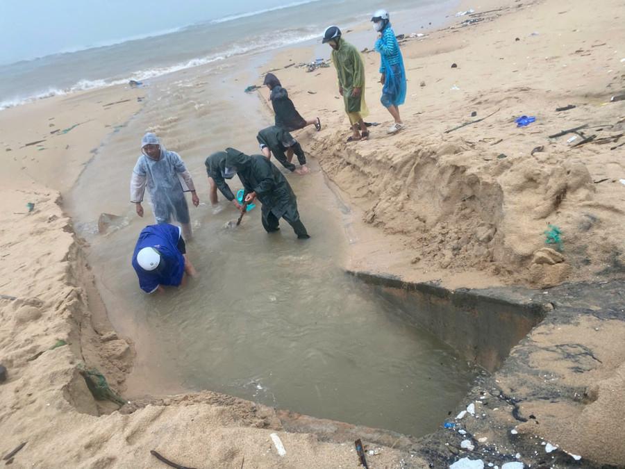 Người dân đội mưa khai thông cống rãnh thoát nước ra biển để giảm bớt ngập úng. Ảnh: Ngọc Nhuận 2078160653141121277.jpg