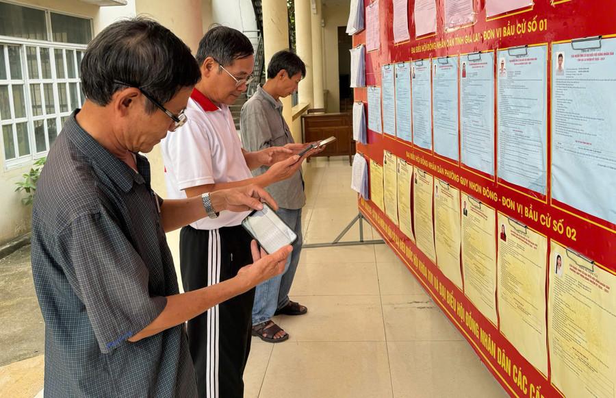 Cử tri khu phố 2 (phường Quy Nhơn Đông) sử dụng điện thoại thông minh để tìm hiểu tiểu sử các ứng cử viên đại biểu Quốc hội và Hội đồng nhân dân các cấp. Ảnh: N.H bau-cu-1-1814.jpg